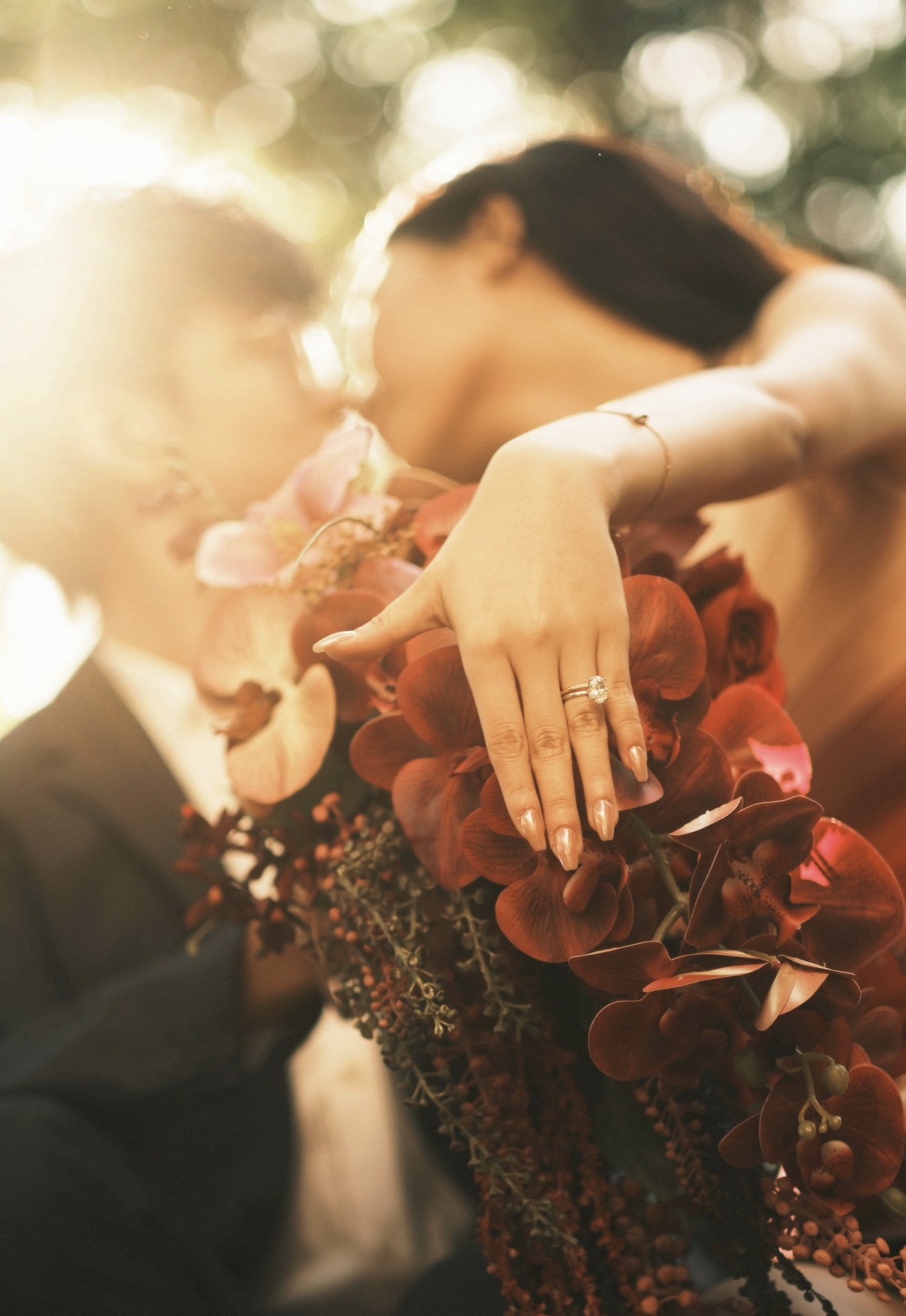 Hand with engagement ring on an orchid bouquet