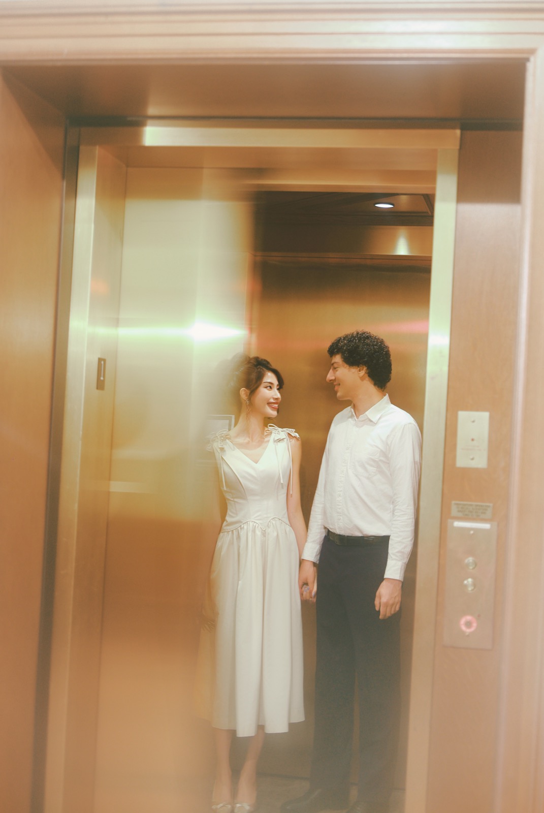Couple holding hands in a gold-toned elevator