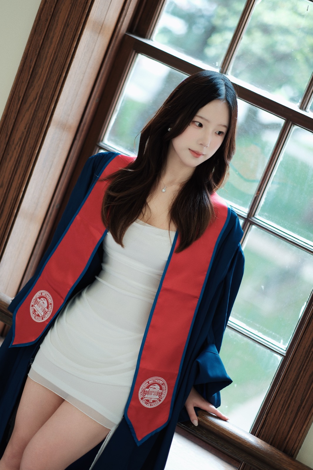 Graduate in gown and stole by a window
