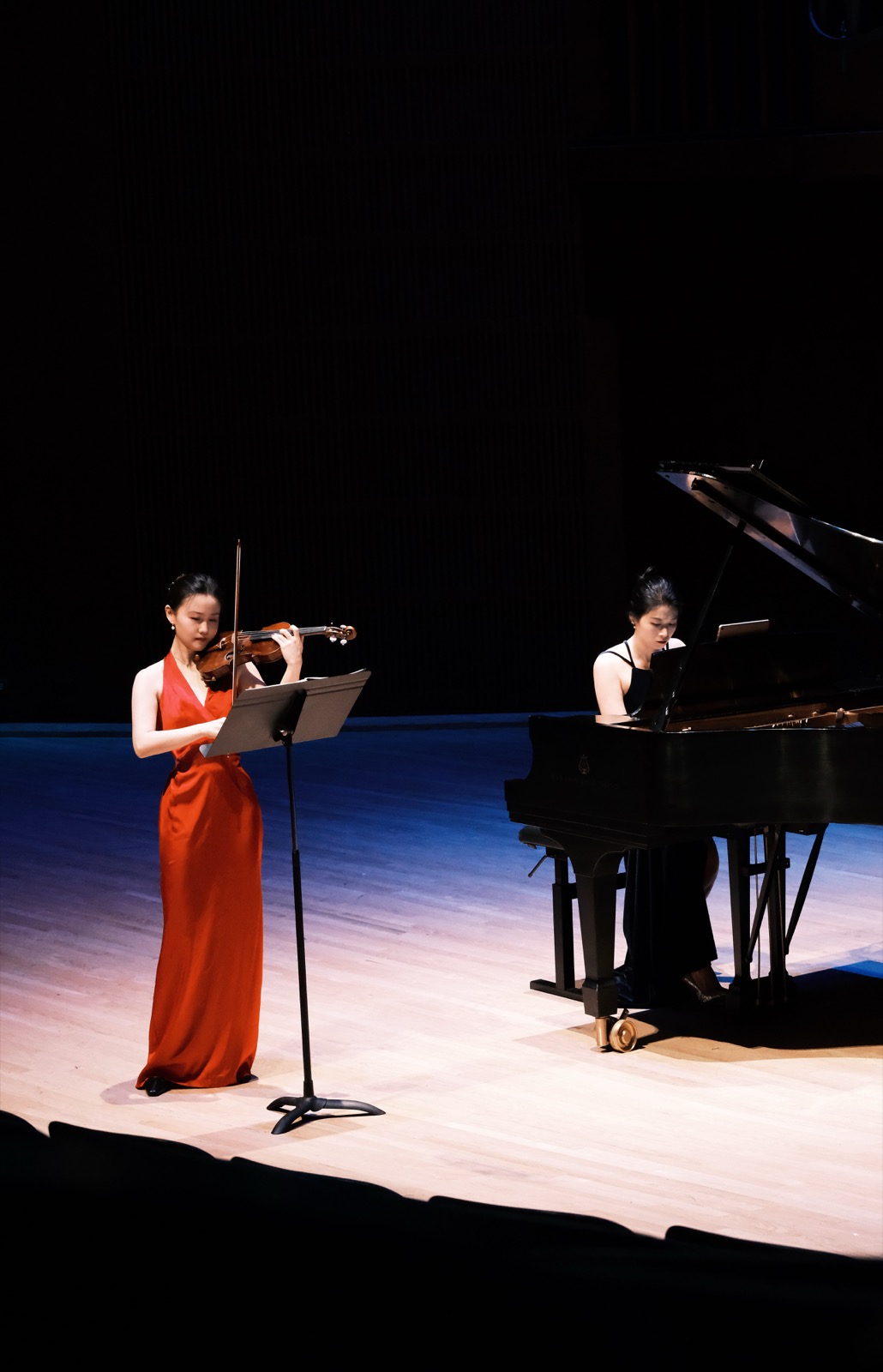 Violinist performing onstage with pianist