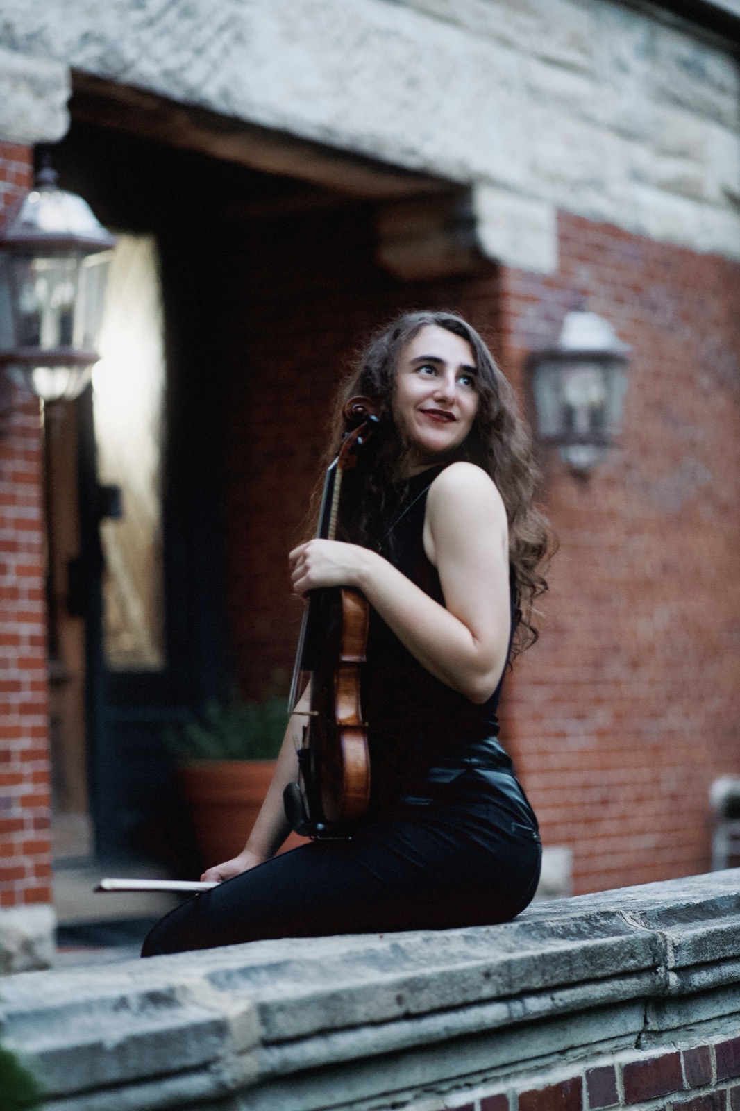 Violinist seated on stone ledge
